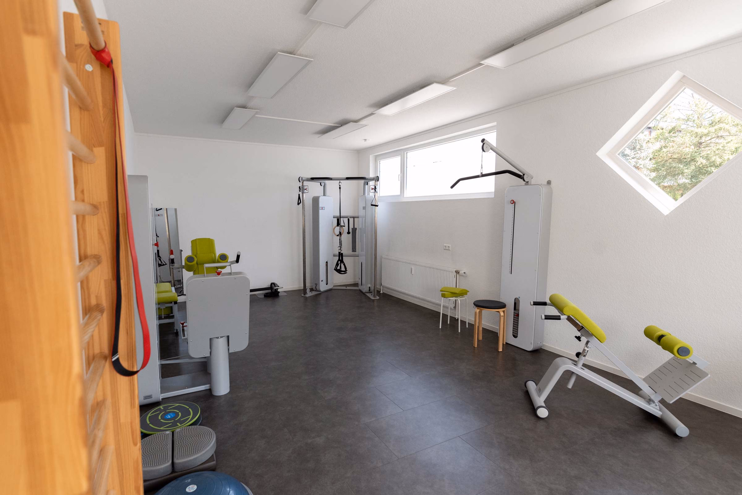 Trainingsraum der Praxis MZ mit Sprossenwand, Kabelzug und Geräten in Limettengrün
