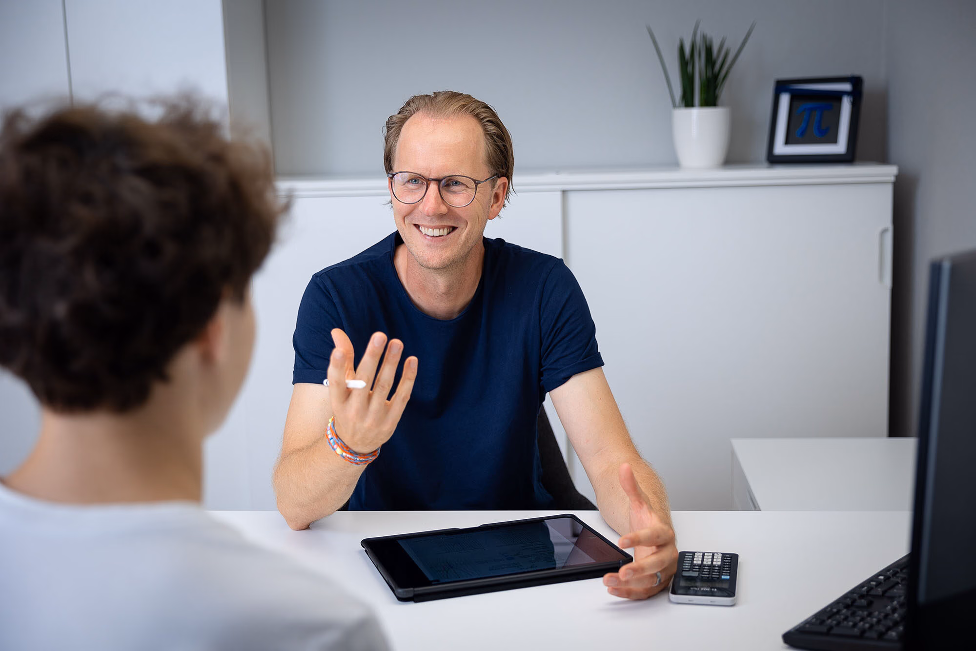 Tillmann Brandt erklärt einem Schüler am Schreibtisch etwas, vor ihm ein Tablet